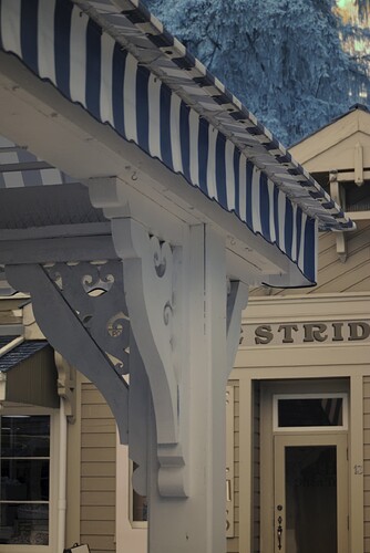 An ornate canopy on a balcony amidst other old buildings. All of the colours are faded and "off".