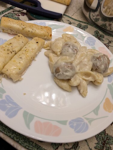 a photo of a plate of meatballs and shells with thick white sauce